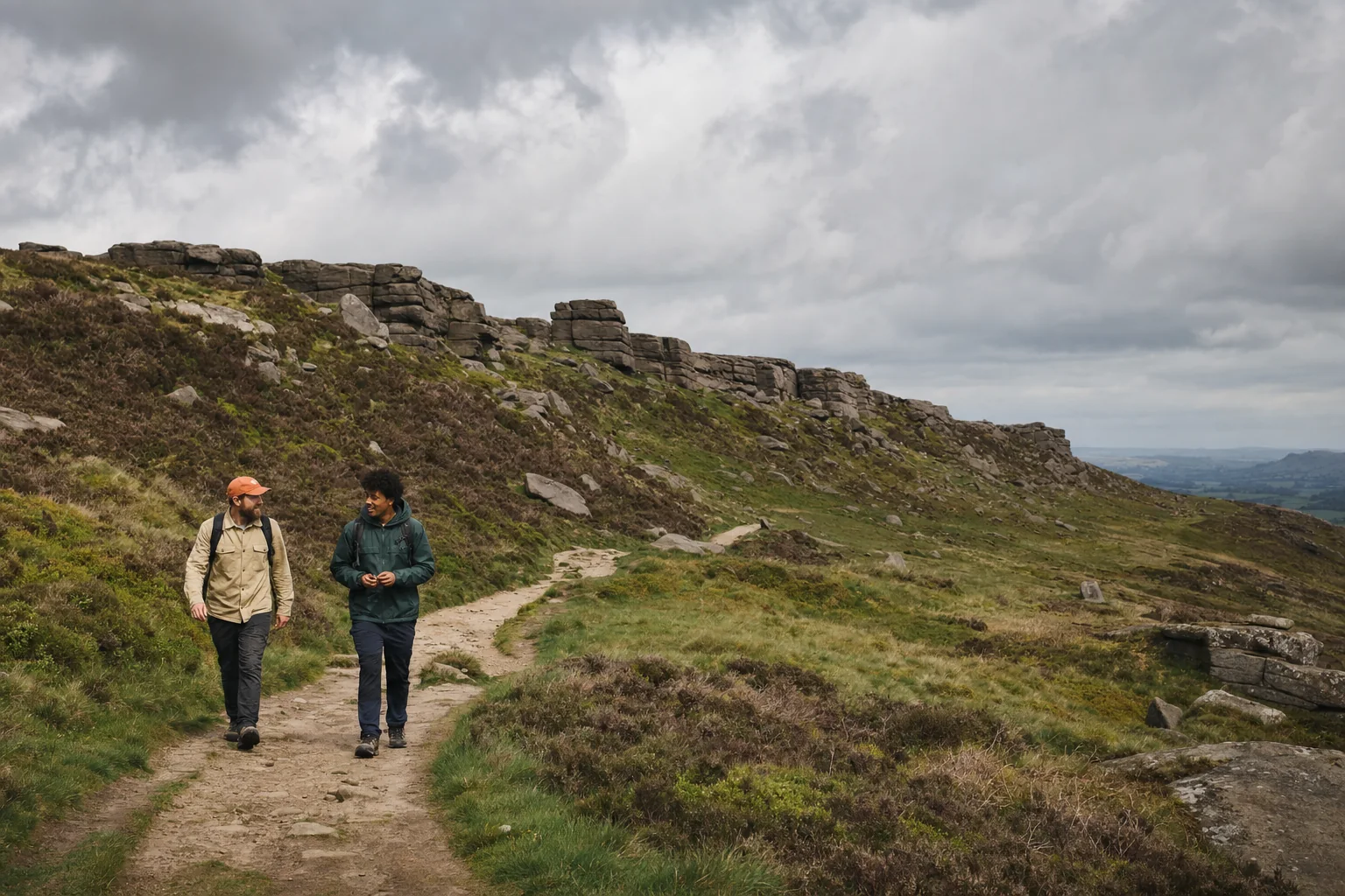 Two walkers on a gritstone trail below a Peak District edge